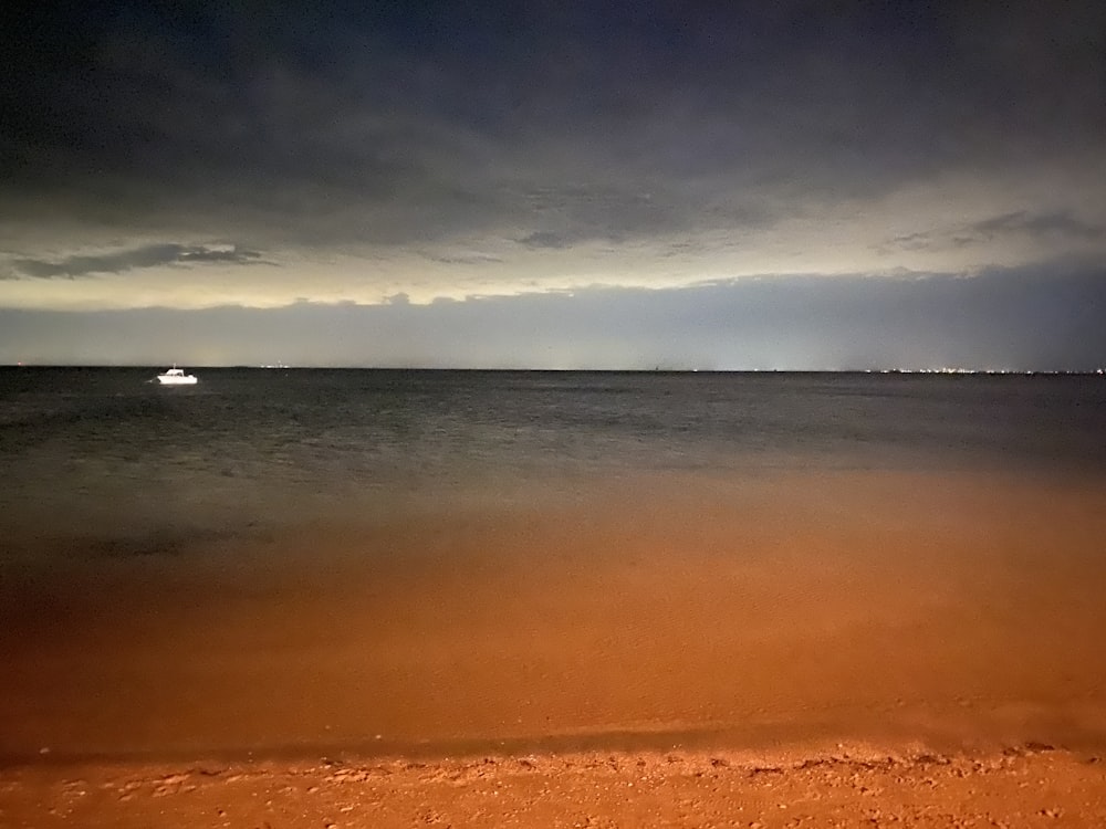 a boat out on the ocean under a cloudy sky