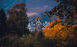 Historic Les Charmettes house surrounded by lush greenery in autumn.