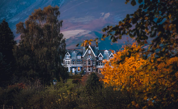Historic Les Charmettes house surrounded by lush greenery in autumn.