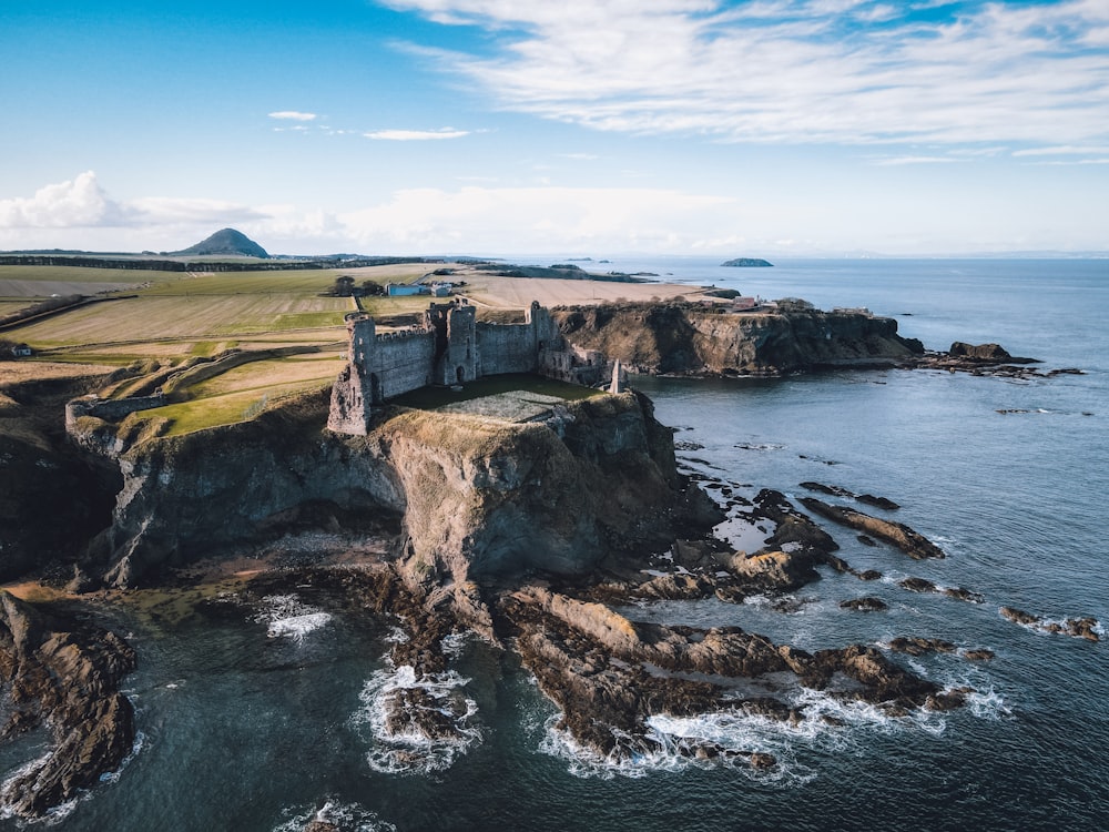 an aerial view of a castle on a cliff near the ocean