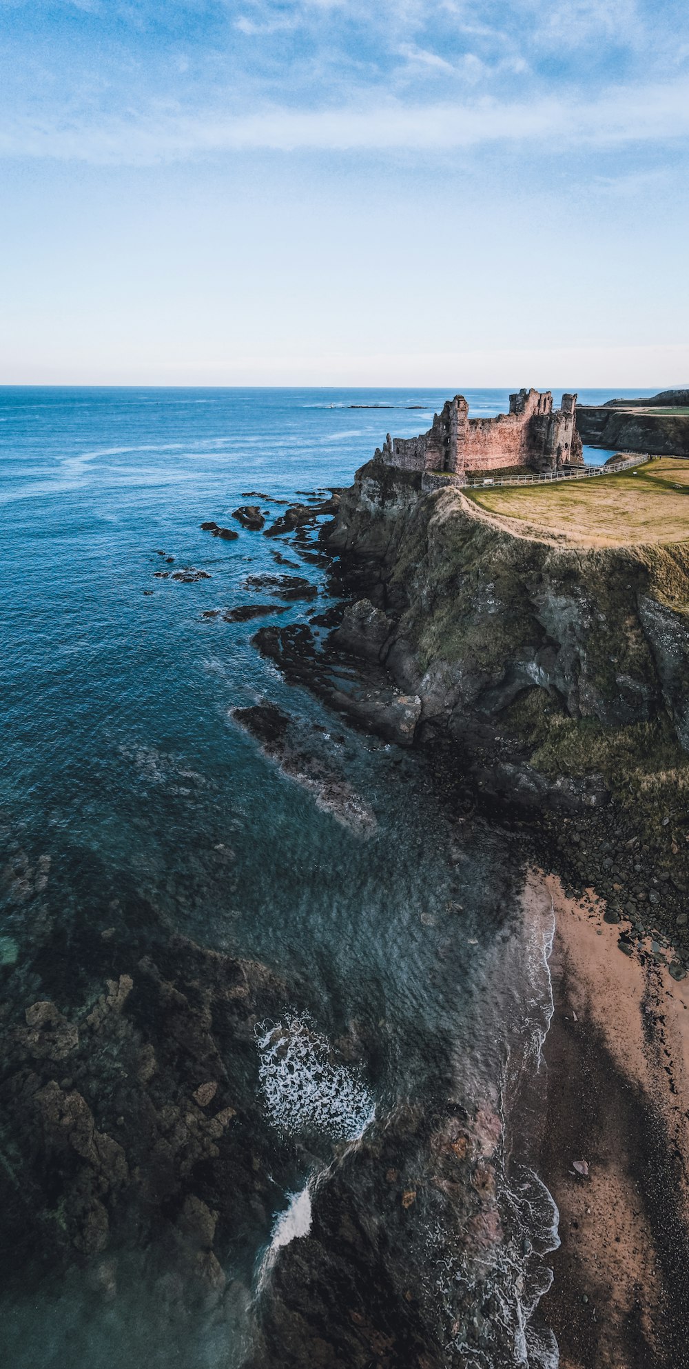 an aerial view of a castle on a cliff overlooking the ocean