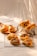 An assortment of freshly baked bread and pastries arranged on a wooden board, a checkered cloth, and a cooling rack. The scene is warmly lit, creating soft shadows and highlighting the golden brown crusts of the baked goods.