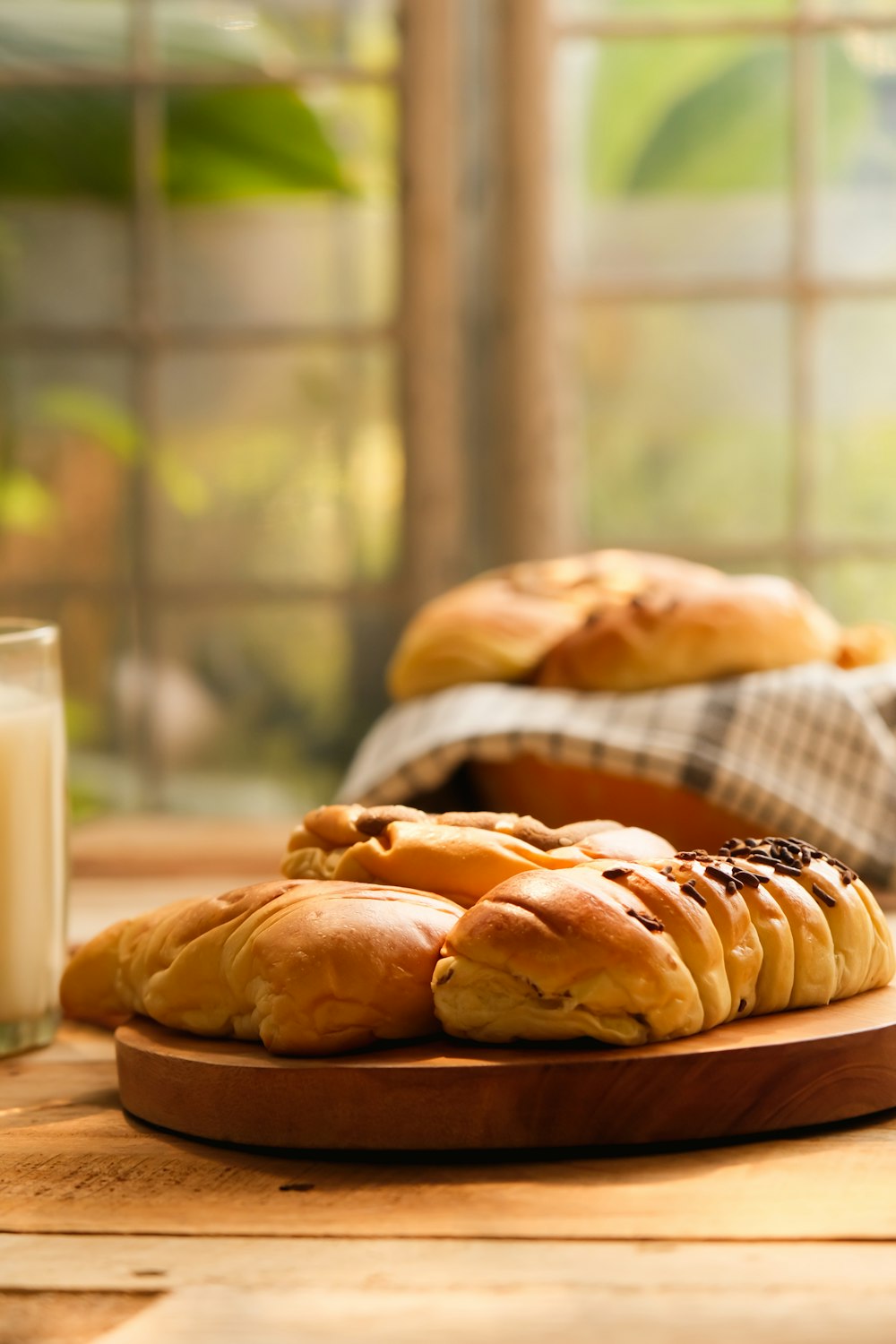 a wooden plate topped with bread next to a glass of milk