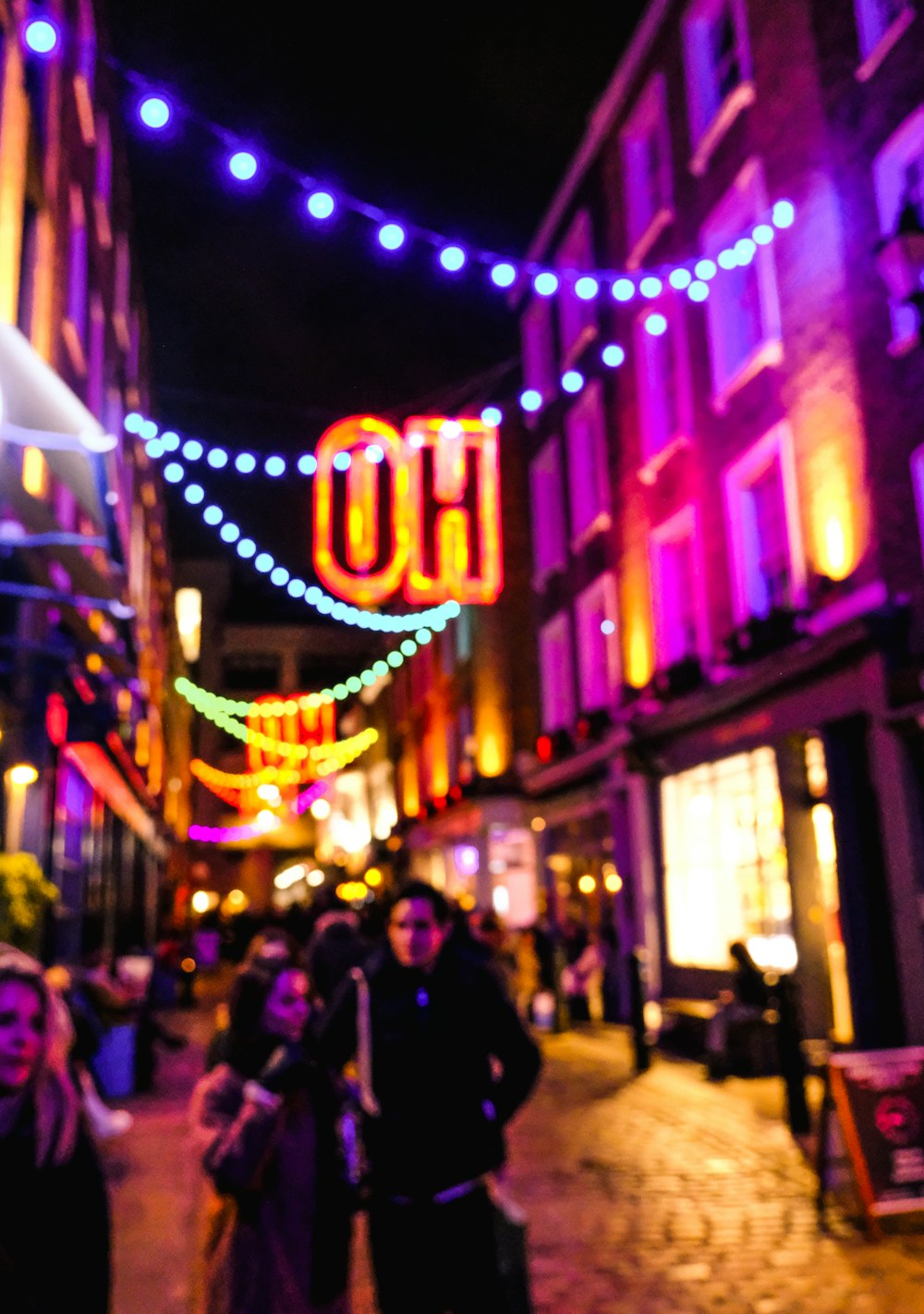 a group of people walking down a street at night