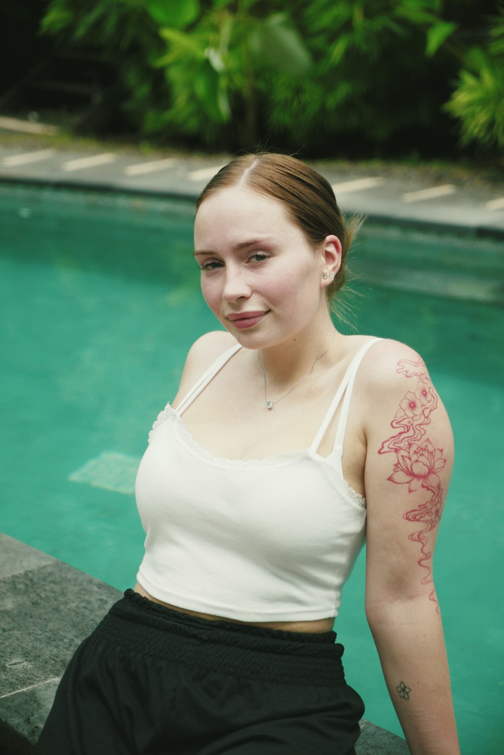 a woman with a tattoo on her arm next to a pool