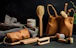 A selection of eco-friendly personal care items including brushes and a pouch, set against a dark background. The arrangement features a variety of wooden brushes with natural bristles and several containers. A fabric pouch and a cloth are also present, adding to the organic feel.