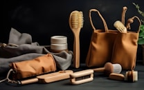A selection of eco-friendly personal care items including brushes and a pouch, set against a dark background. The arrangement features a variety of wooden brushes with natural bristles and several containers. A fabric pouch and a cloth are also present, adding to the organic feel.