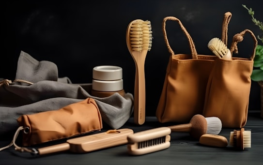 A selection of eco-friendly personal care items including brushes and a pouch, set against a dark background. The arrangement features a variety of wooden brushes with natural bristles and several containers. A fabric pouch and a cloth are also present, adding to the organic feel.