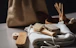 A collection of eco-friendly personal hygiene items is arranged on a soft, white fabric. Included are a wooden brush with natural bristles, a loofah, and other bamboo or wooden accessories, suggesting a focus on sustainability. The scene is softly lit, and a burlap bag is subtly visible in the blurred background.