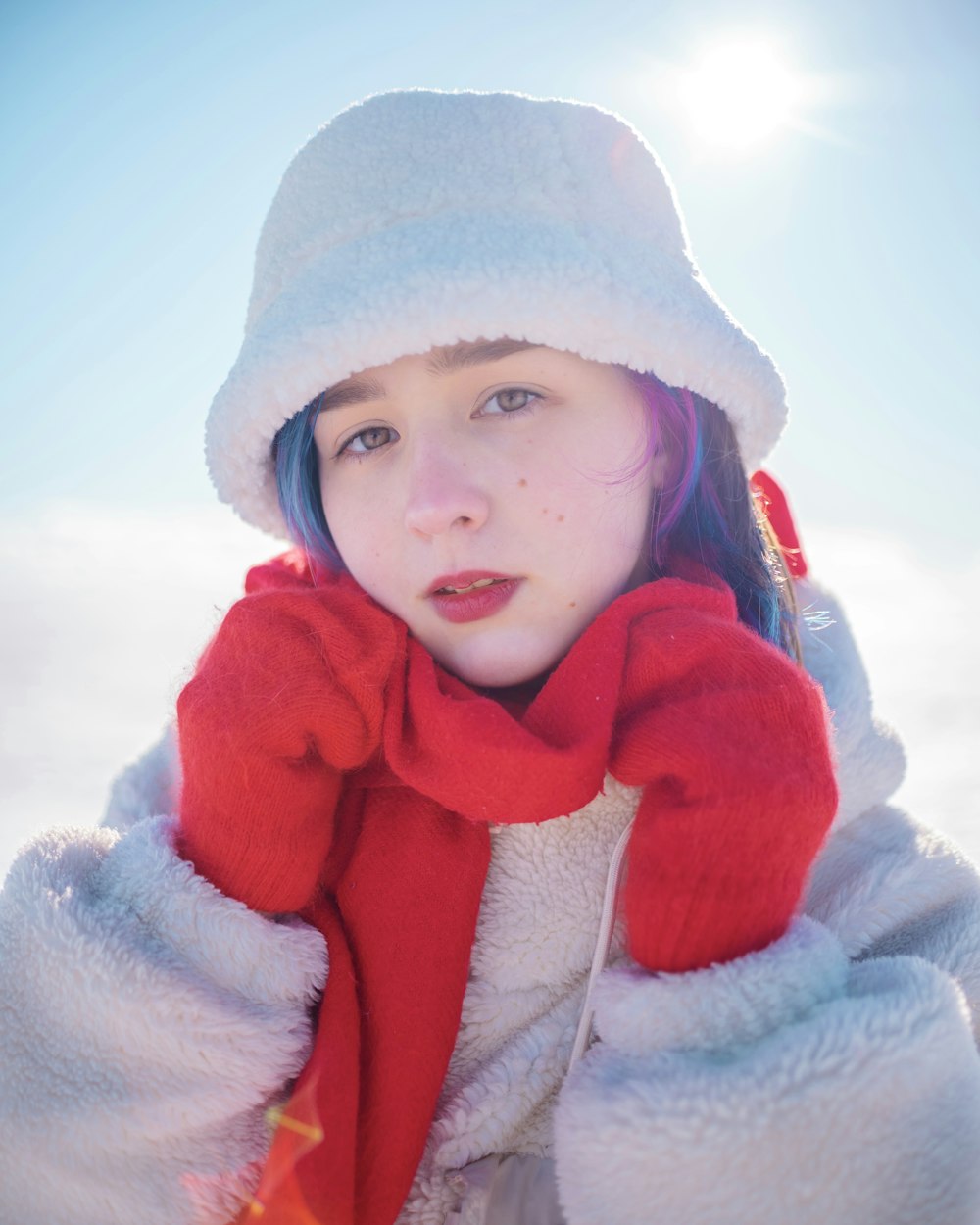 a young woman wearing a red scarf and a white hat