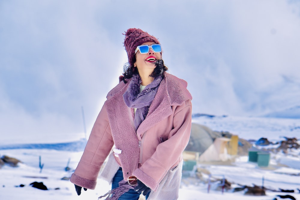 a woman wearing sunglasses and a pink coat in the snow