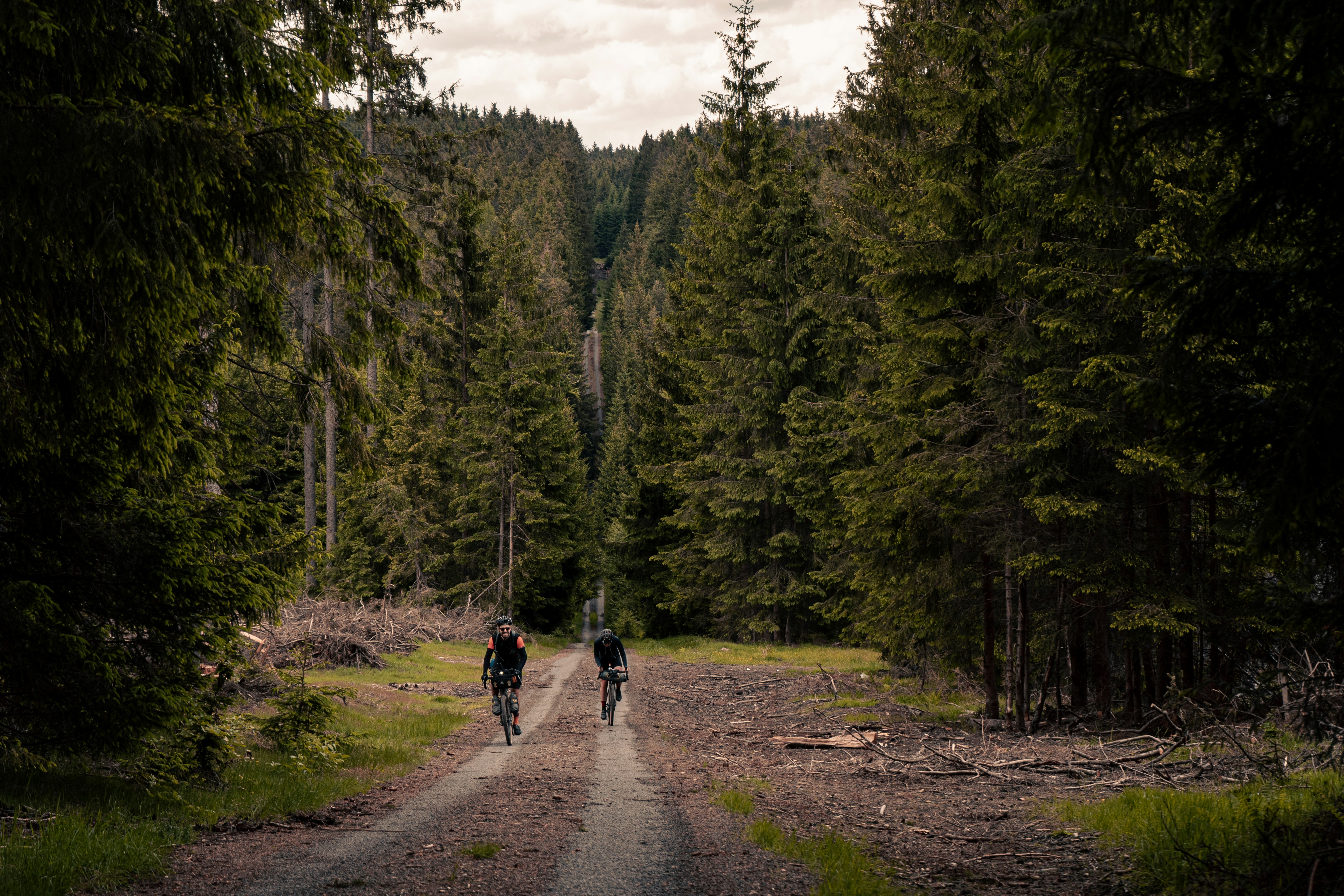 a couple of people riding bikes down a dirt road