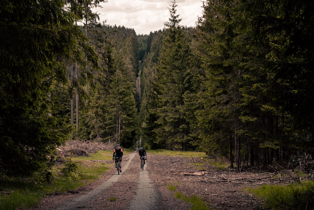 a couple of people riding bikes down a dirt road