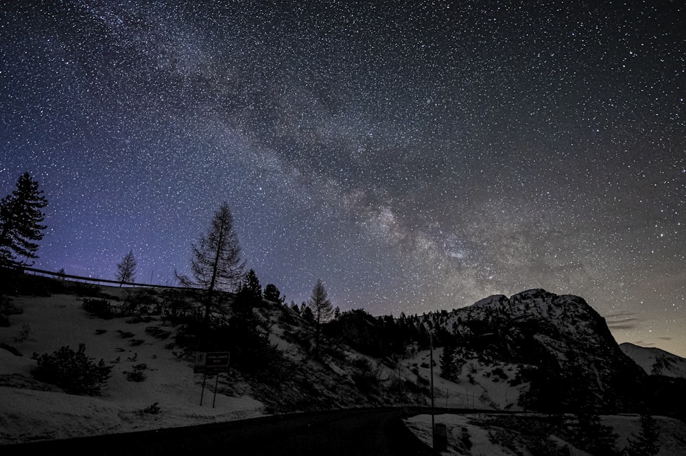 the night sky with stars above a mountain