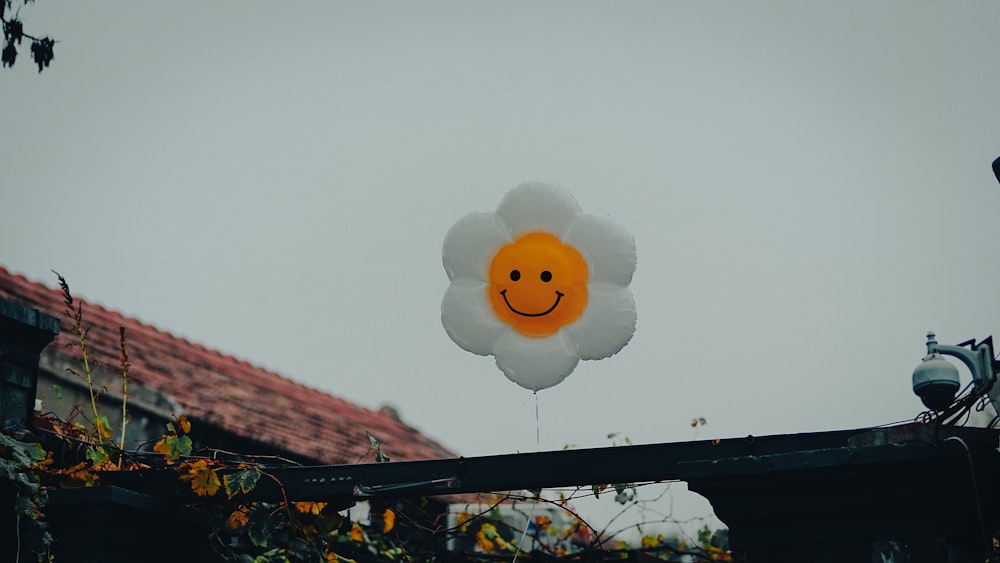 a smiley face balloon floating in the air