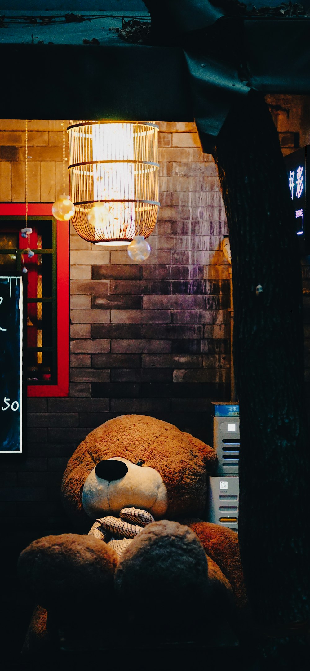a large teddy bear sitting in front of a brick wall