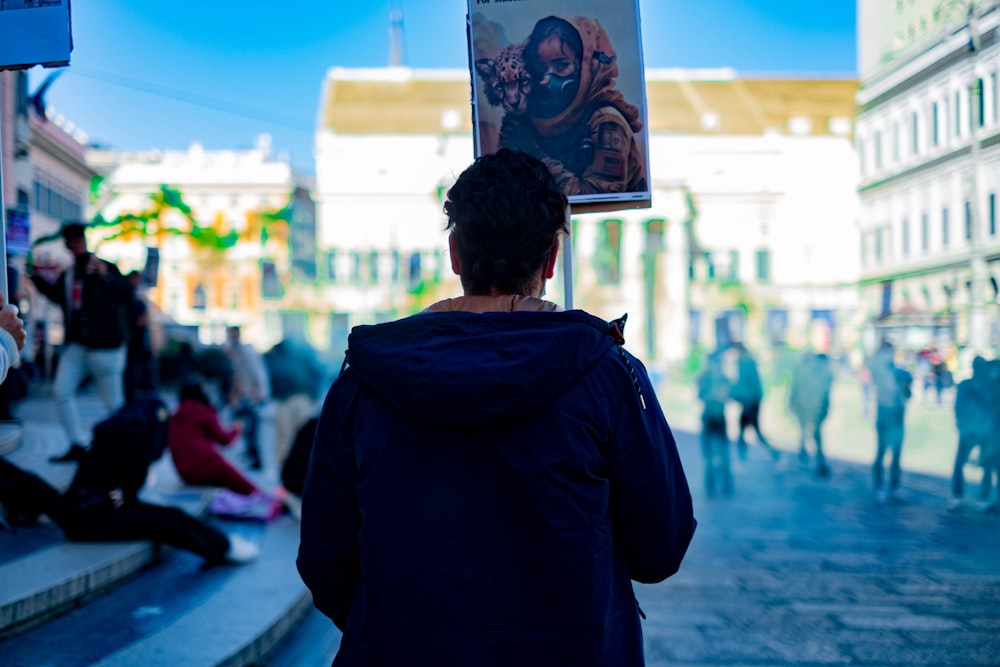 a man walking down a street holding a picture of a woman