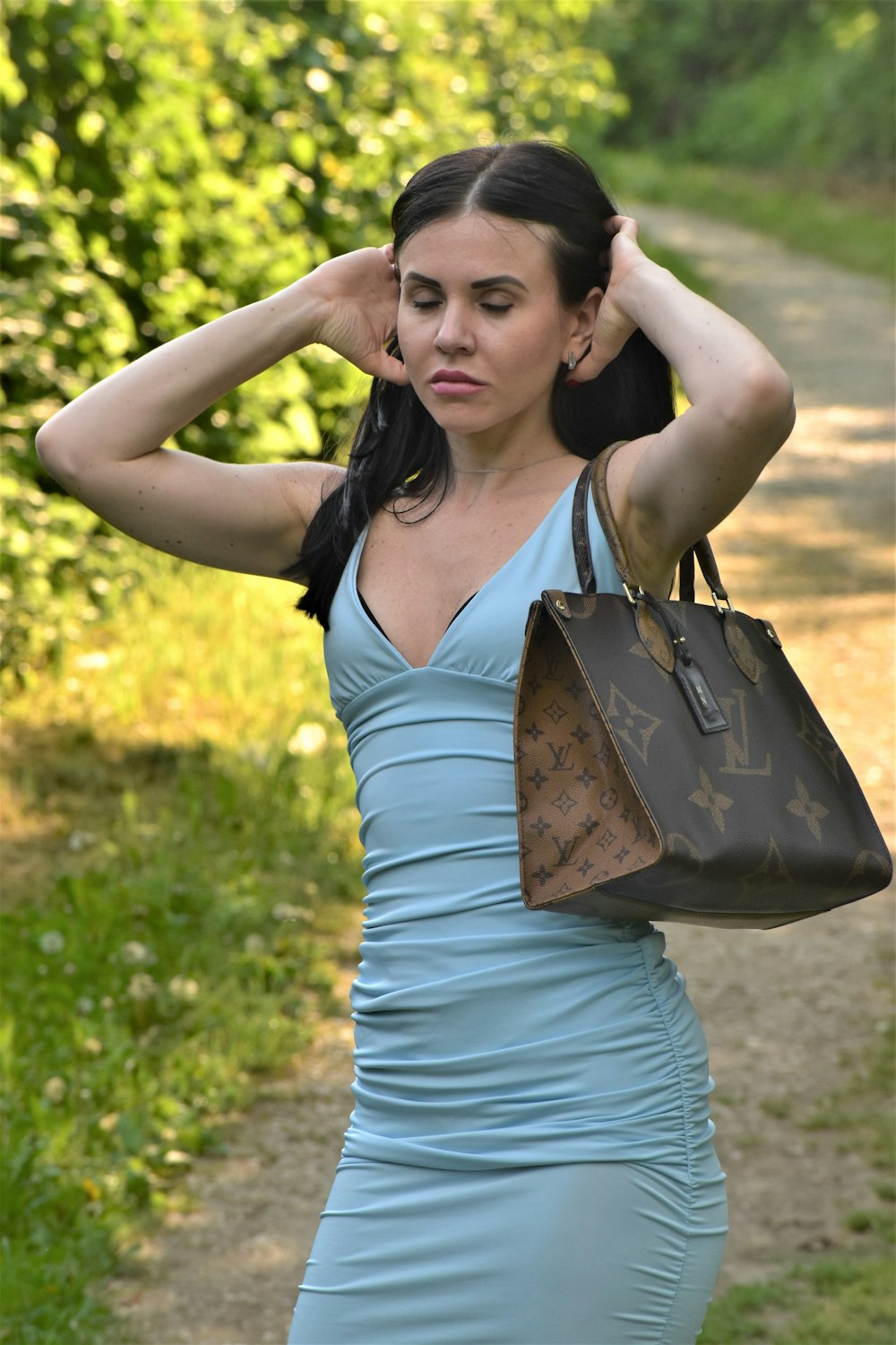 a woman in a blue dress holding a brown purse