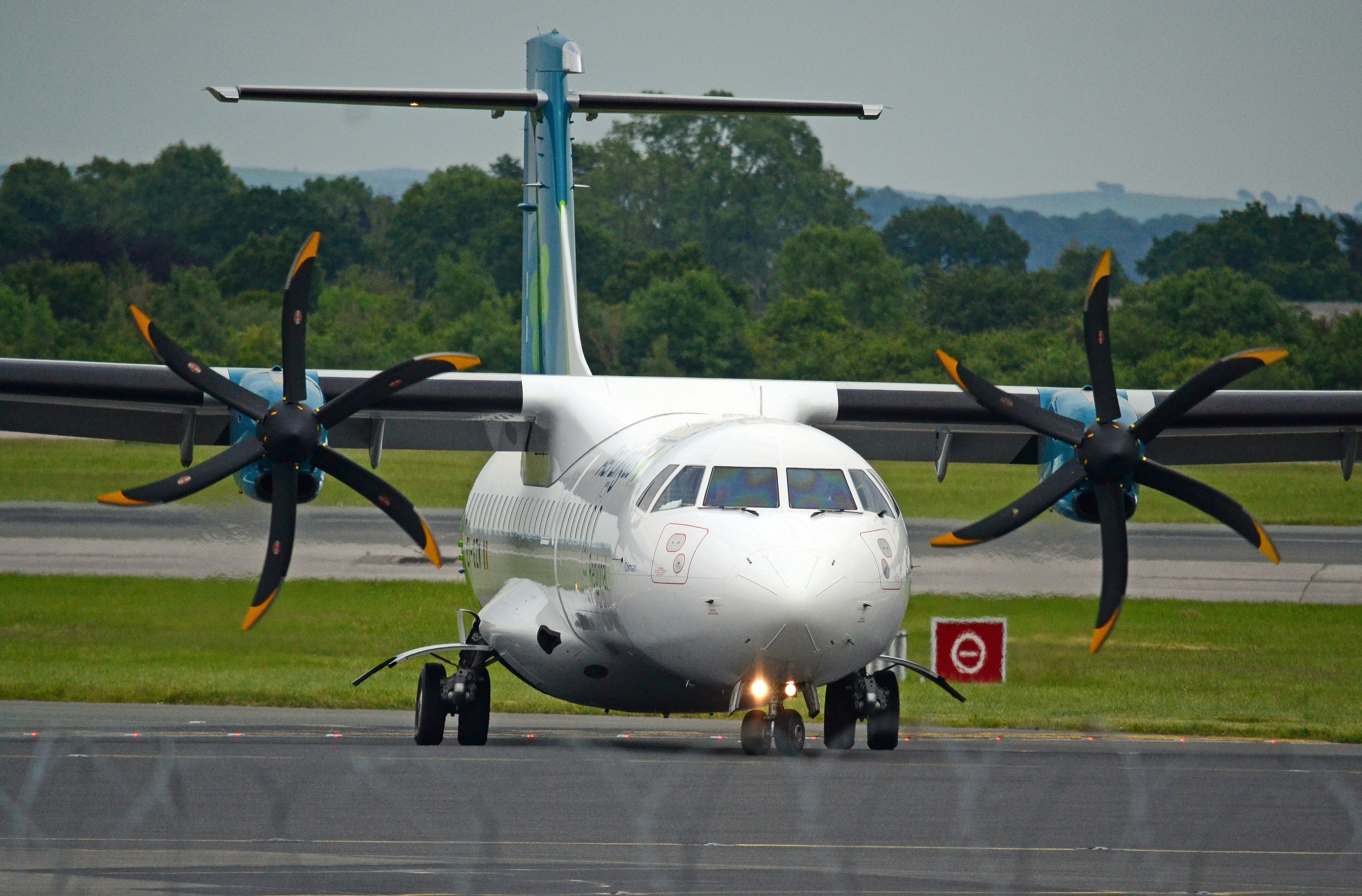 a large propeller plane sitting on top of an airport runway, Planes landing/taking off at Manchester Airport, UK.