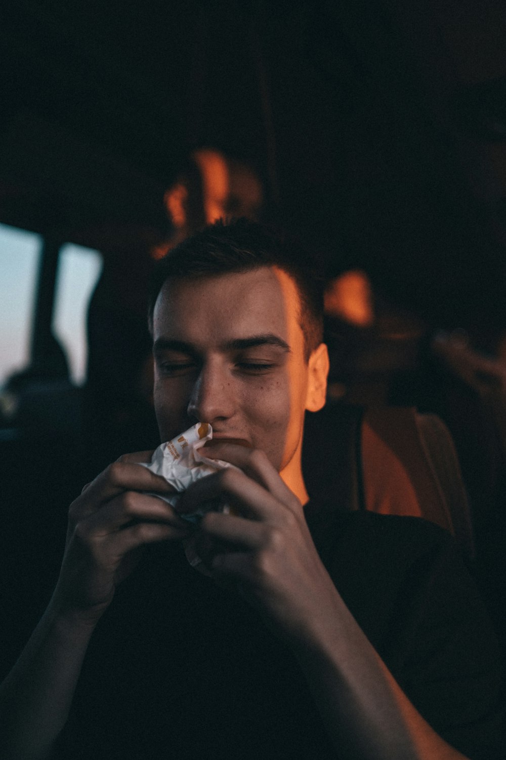 a man sitting in a car eating a piece of food