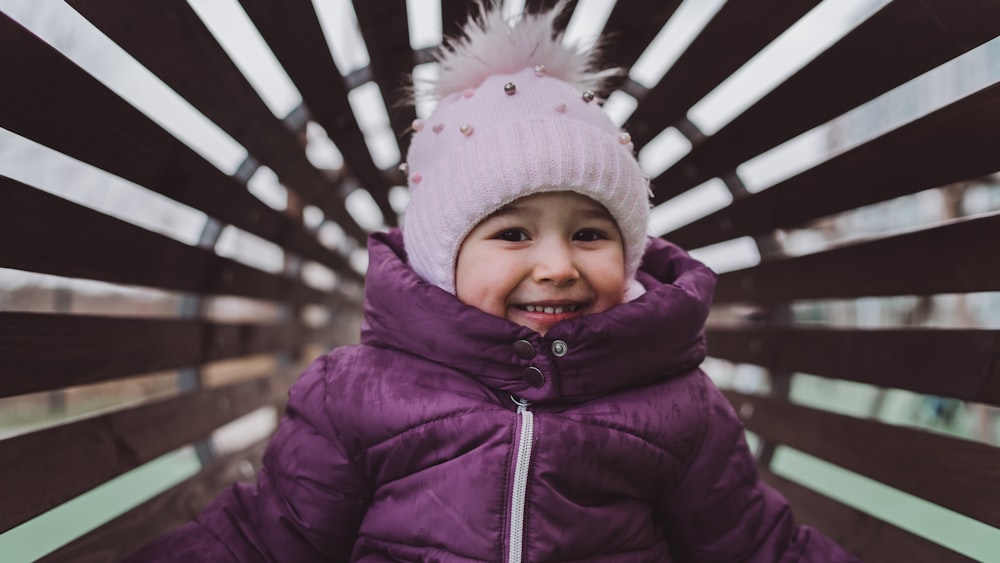 a little girl sitting on a bench in a park