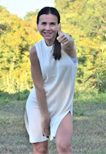 Smiling businesswoman giving a thumbs up next to a water purification system.