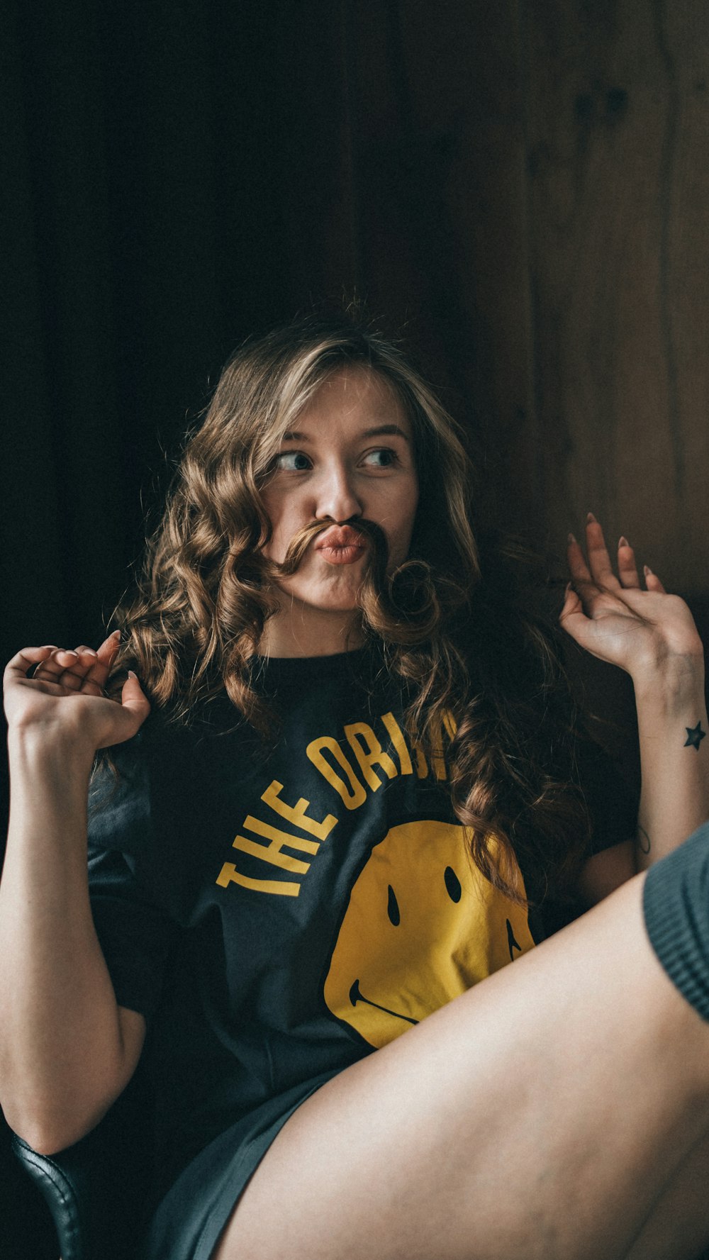 a woman sitting on a chair with a mustache in her mouth