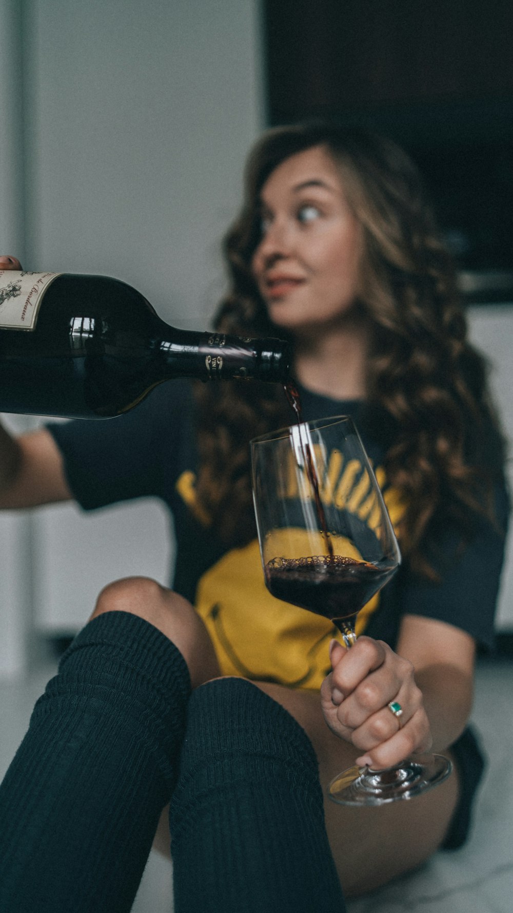 a woman sitting on the floor with a glass of wine