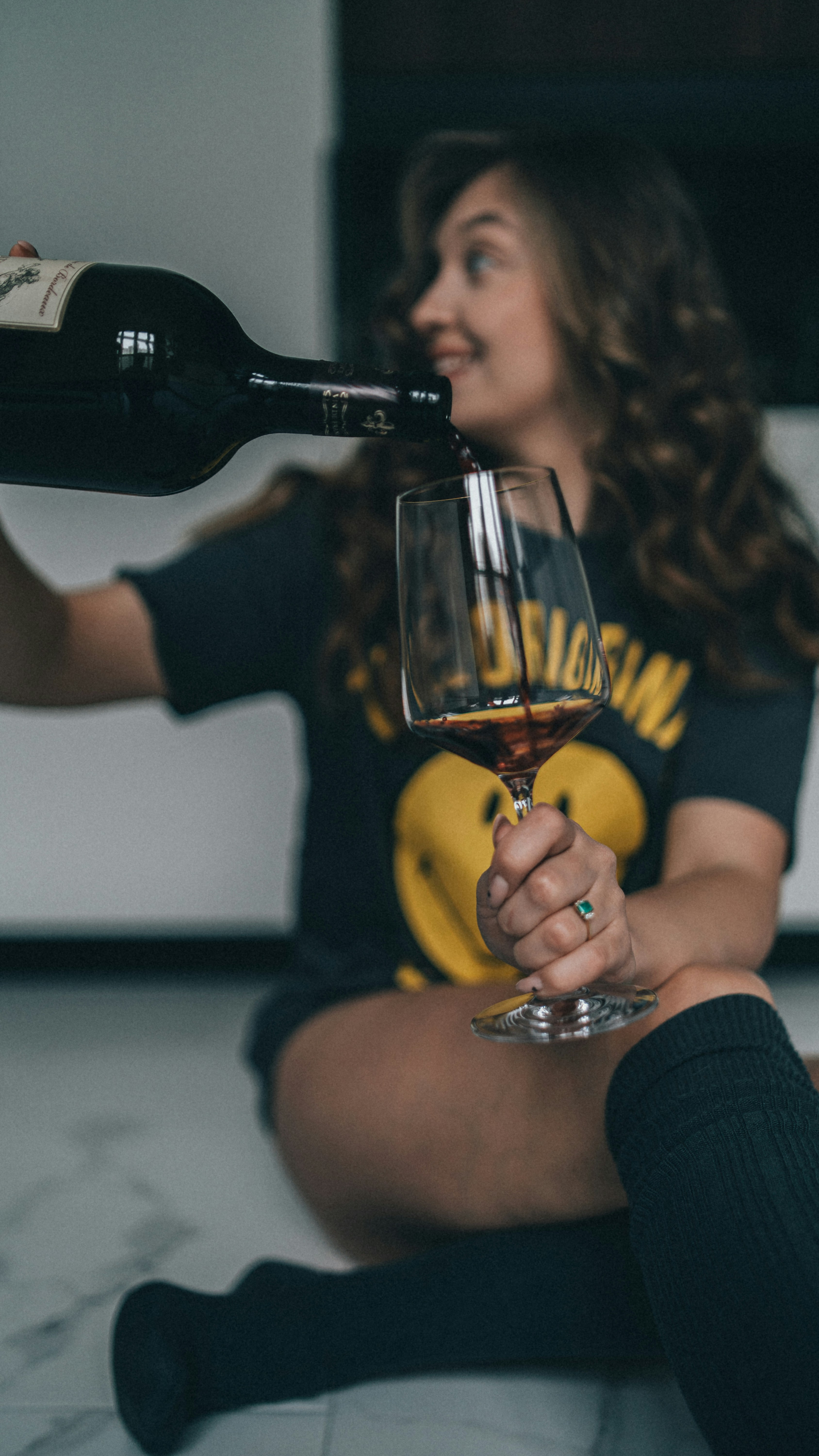 a woman sitting on the floor with a glass of wine