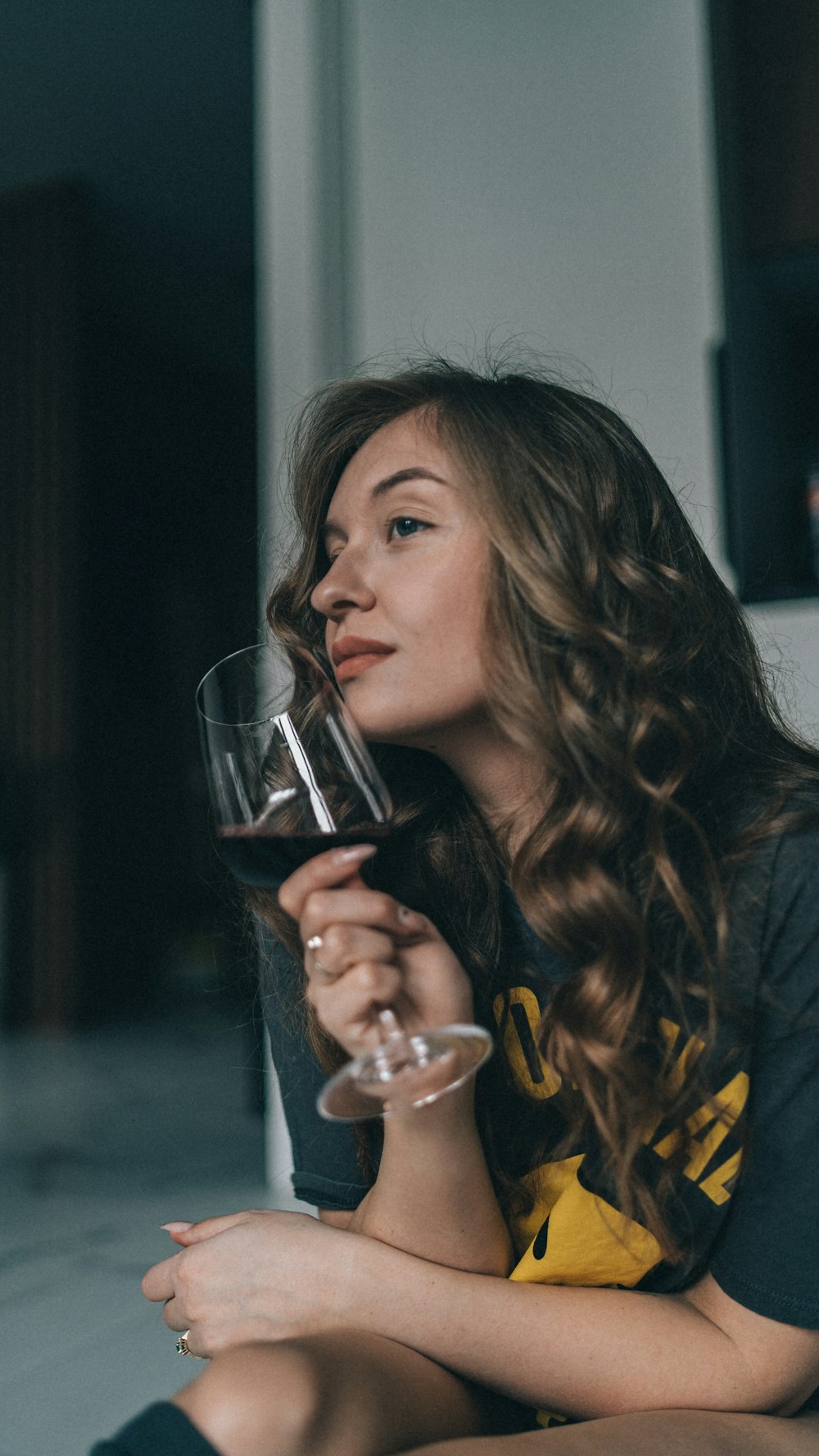 와인 한 잔을 들고 바닥에 앉아 있는 여자