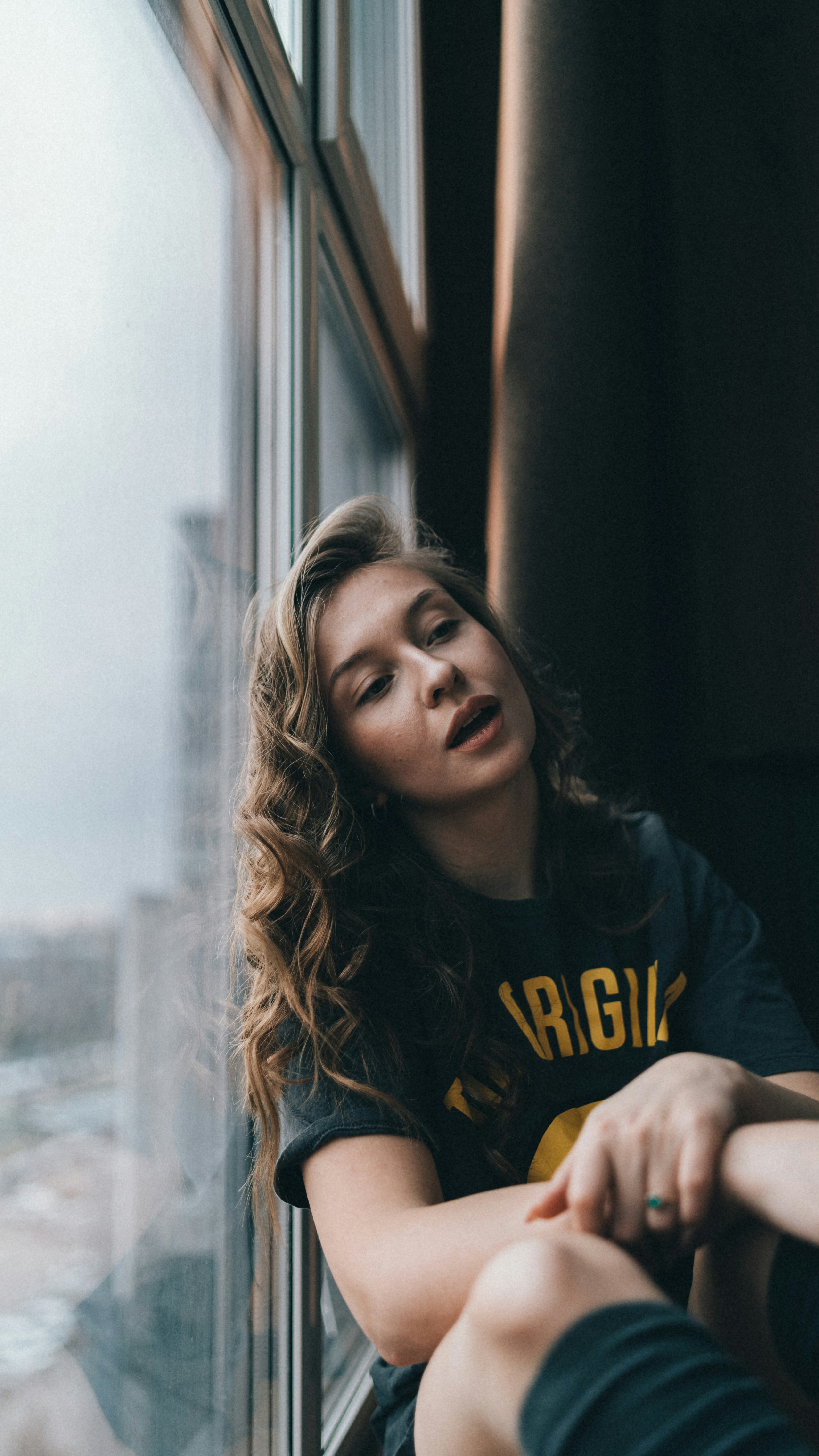 a woman sitting on a window sill looking out the window