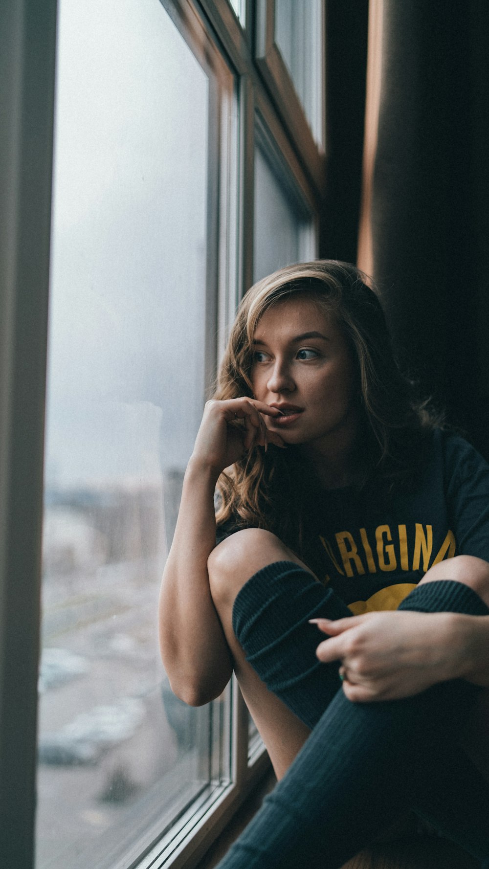 a woman sitting on a window sill looking out the window