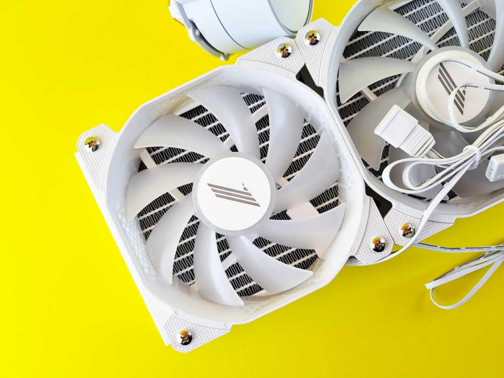 a white computer fan sitting on top of a yellow surface
