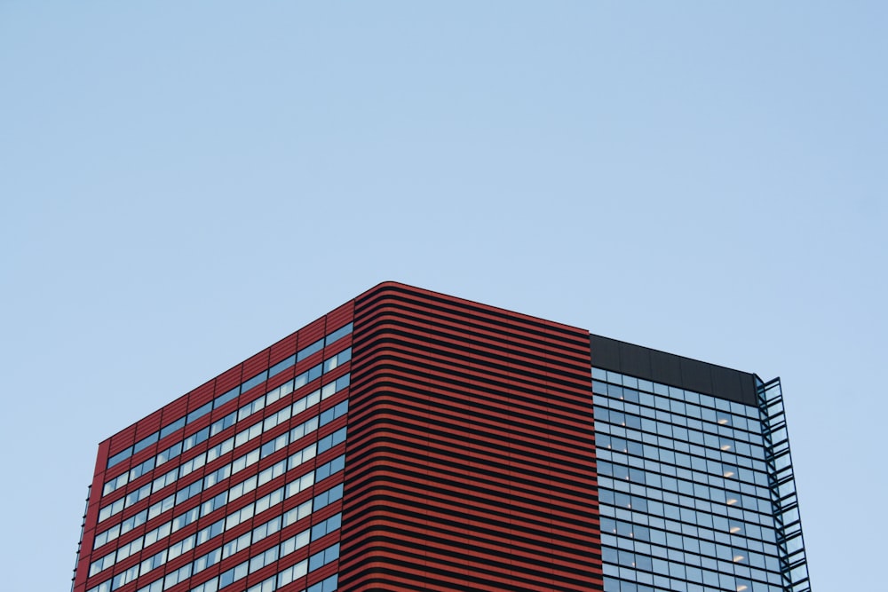 a very tall red and black building with a sky background