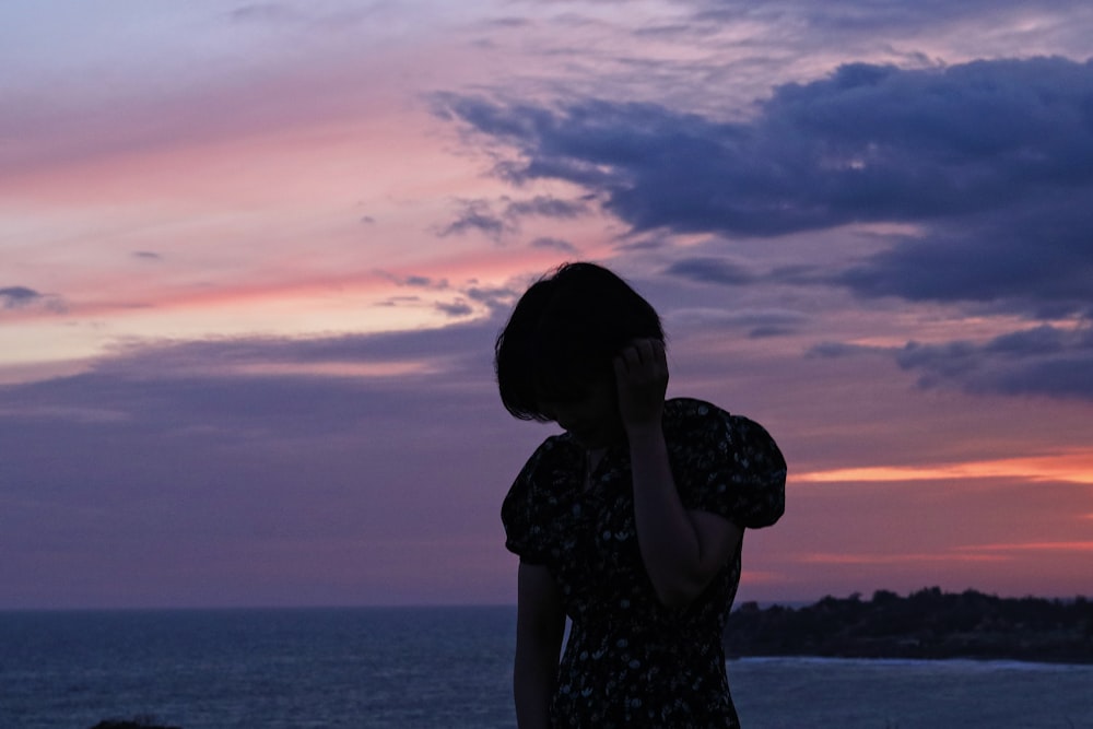 a woman standing in front of a body of water