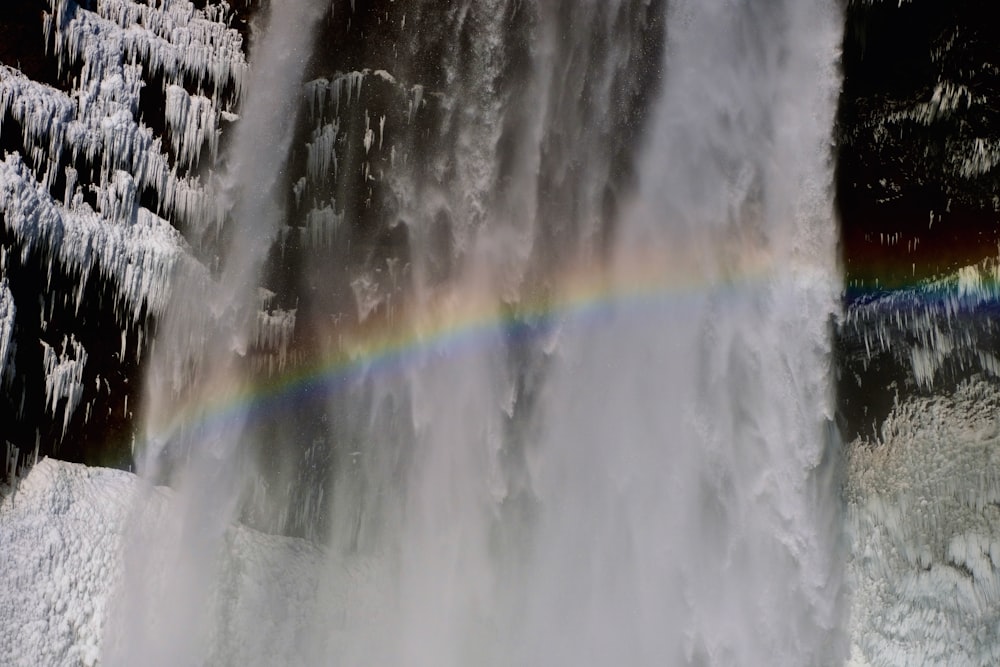 uma cachoeira com um arco-íris no meio dela