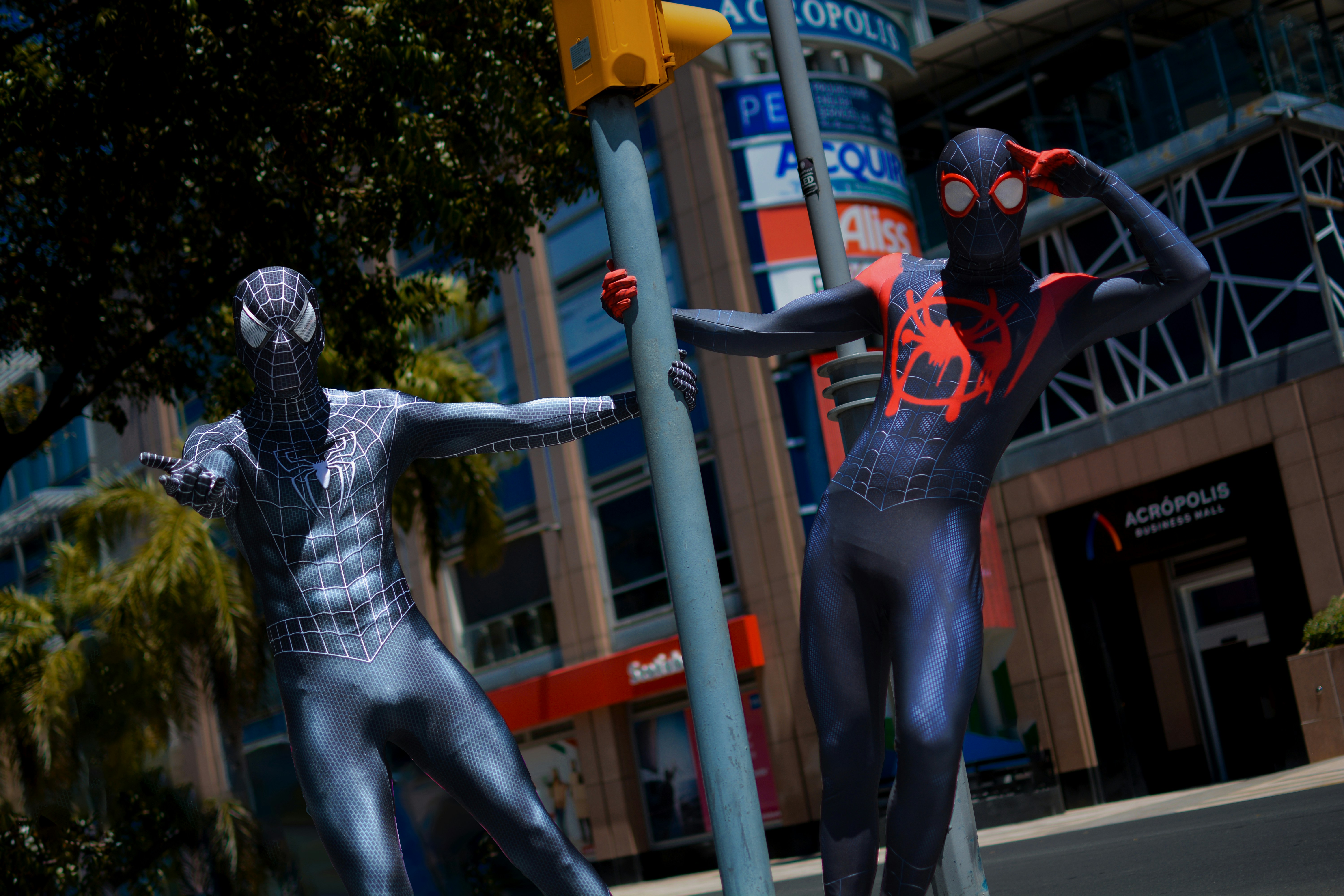 a couple of men in spider man suits standing next to each other