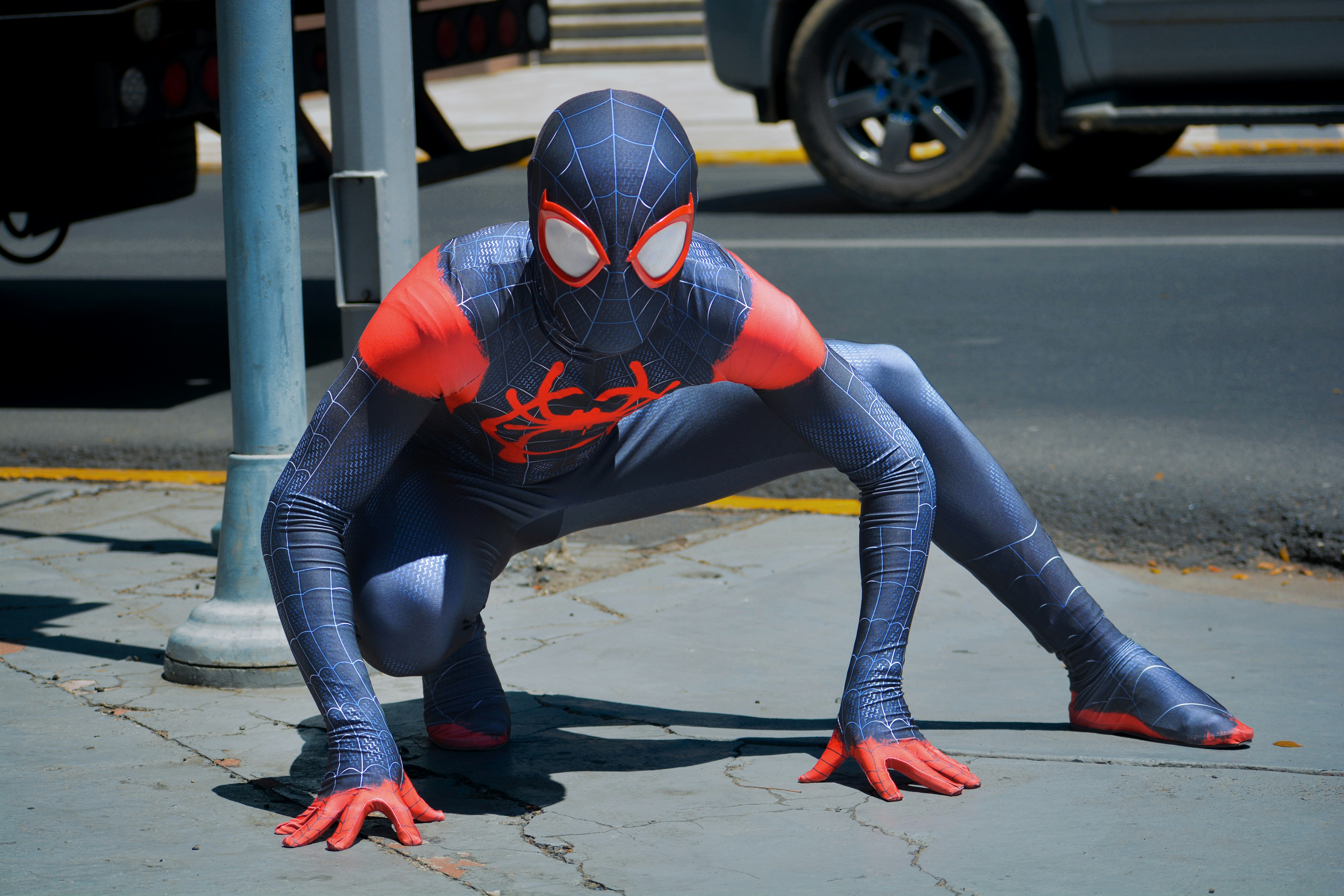 Seorang pria berjas Spider Man di trotoar
