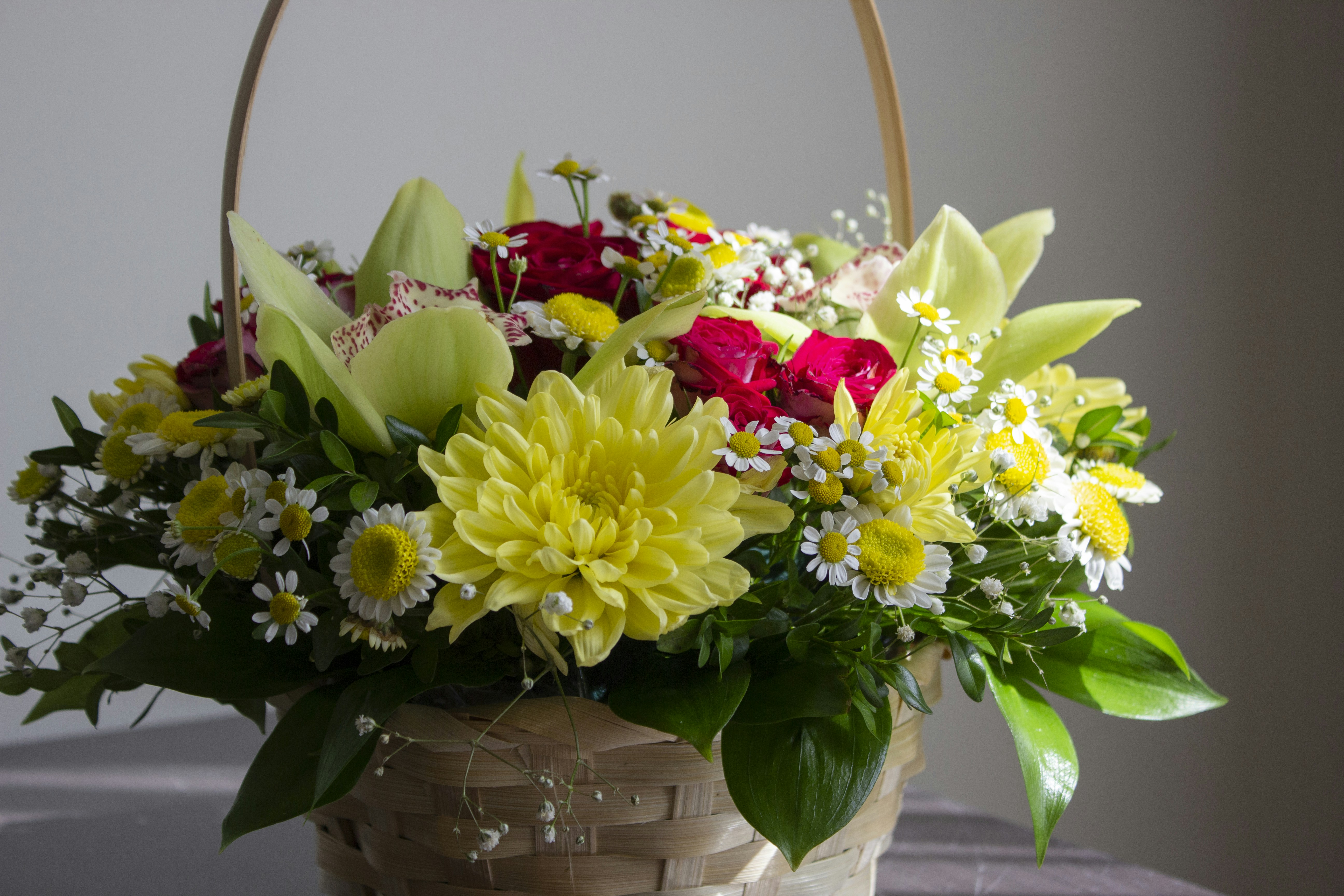 Una canasta llena de muchas flores sentada encima de una mesa