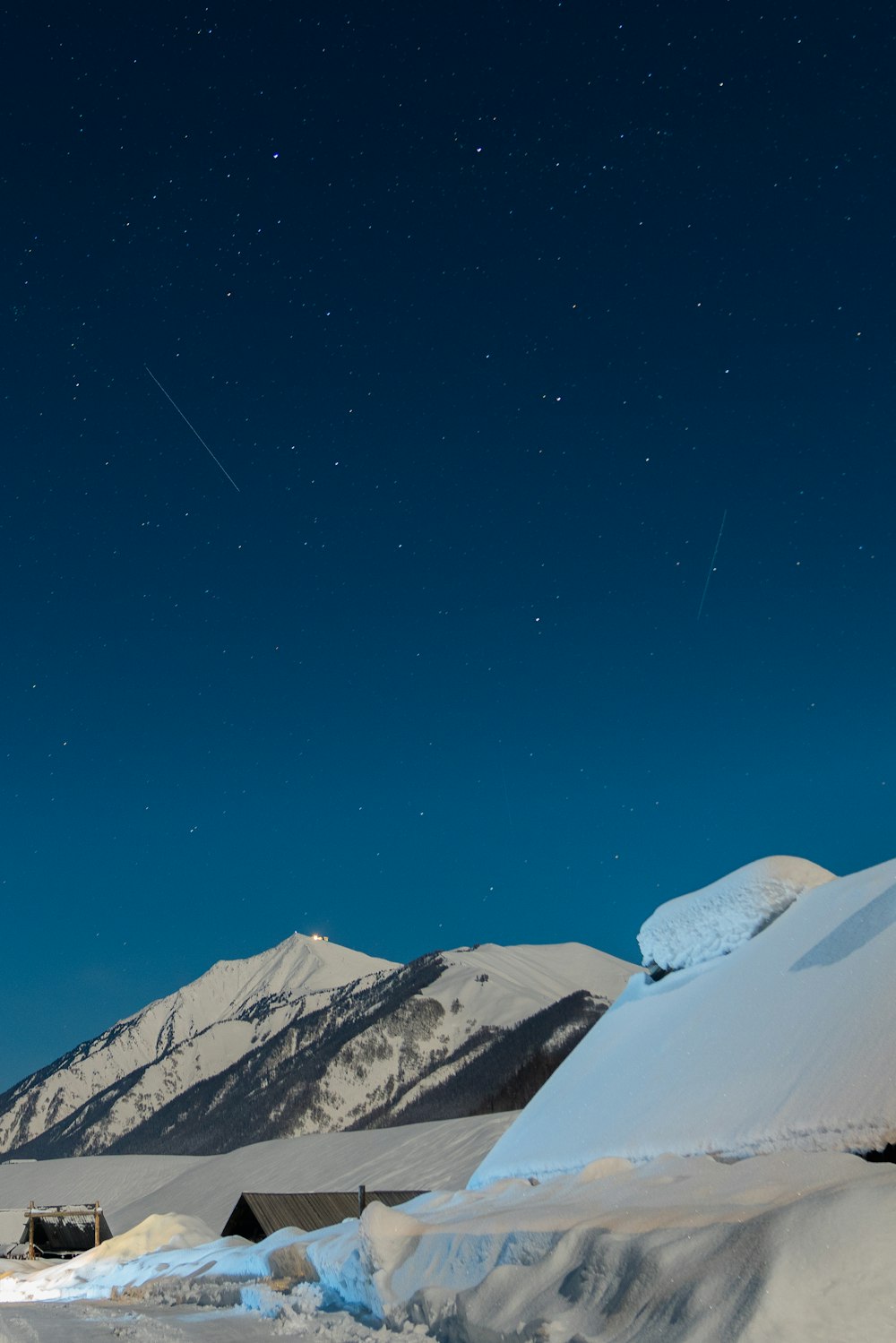 the night sky over a snow covered mountain range