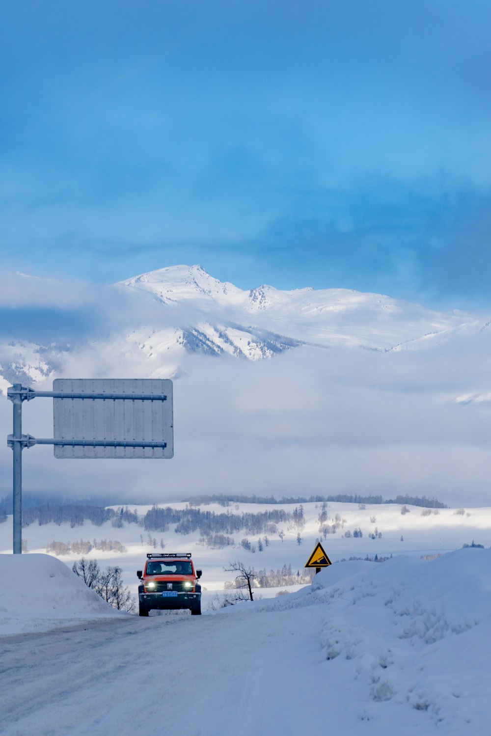 a truck driving down a snow covered road