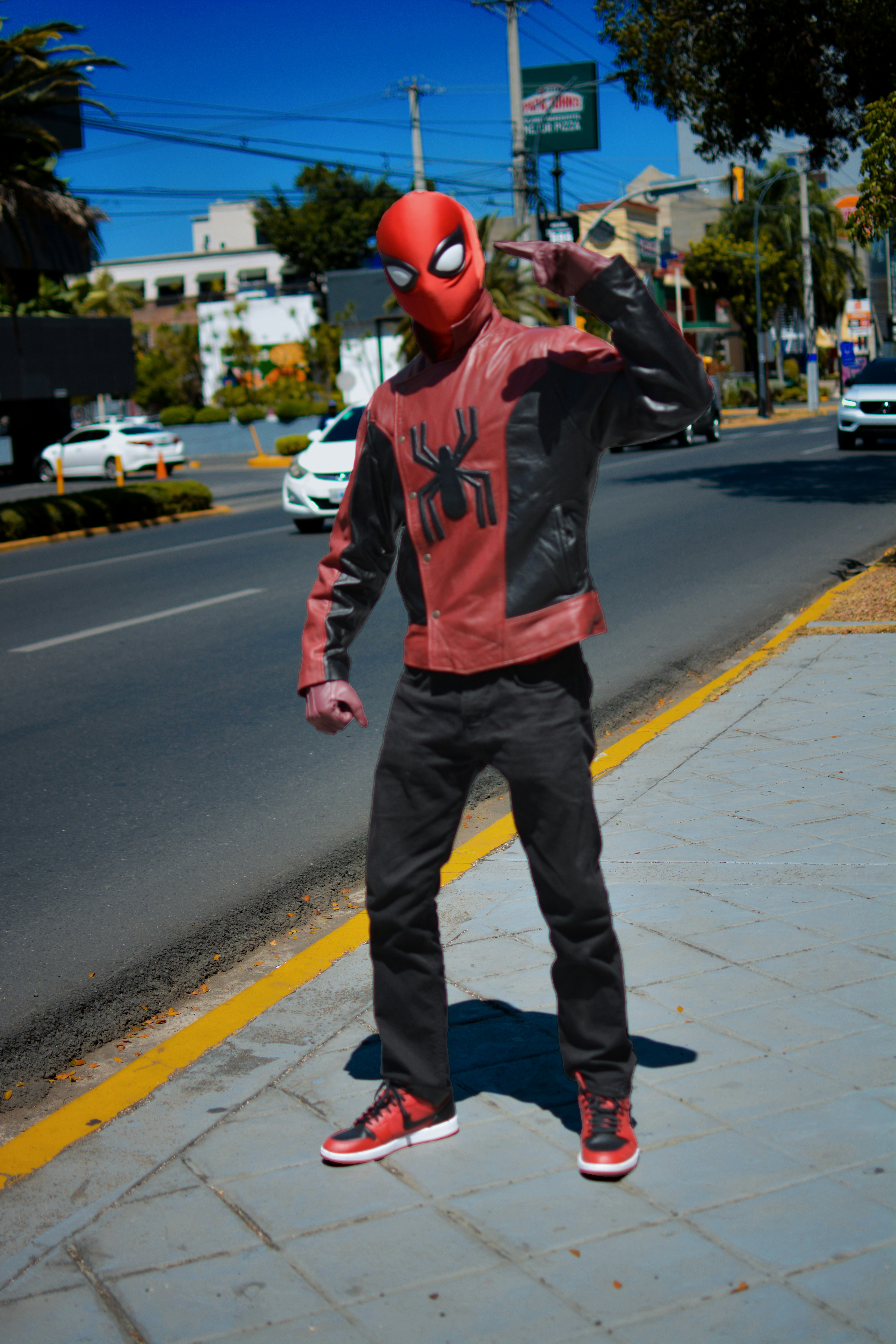 Seorang pria berkostum Spiderman berdiri di trotoar