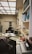 An office space cluttered with various office supplies and equipment. There are several chairs, desks filled with papers, books, and vintage electronics including a CRT monitor, keyboard, and an old typewriter. Shelves filled with binders, books, and file organizers are visible. Lighting is provided by a grid of ceiling panels.