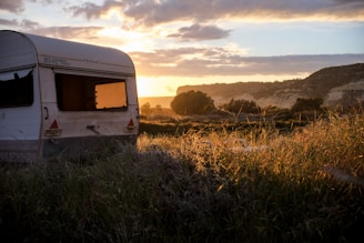 A vibrant sunset casting golden light over the caravan as it rests beneath eucalyptus trees.