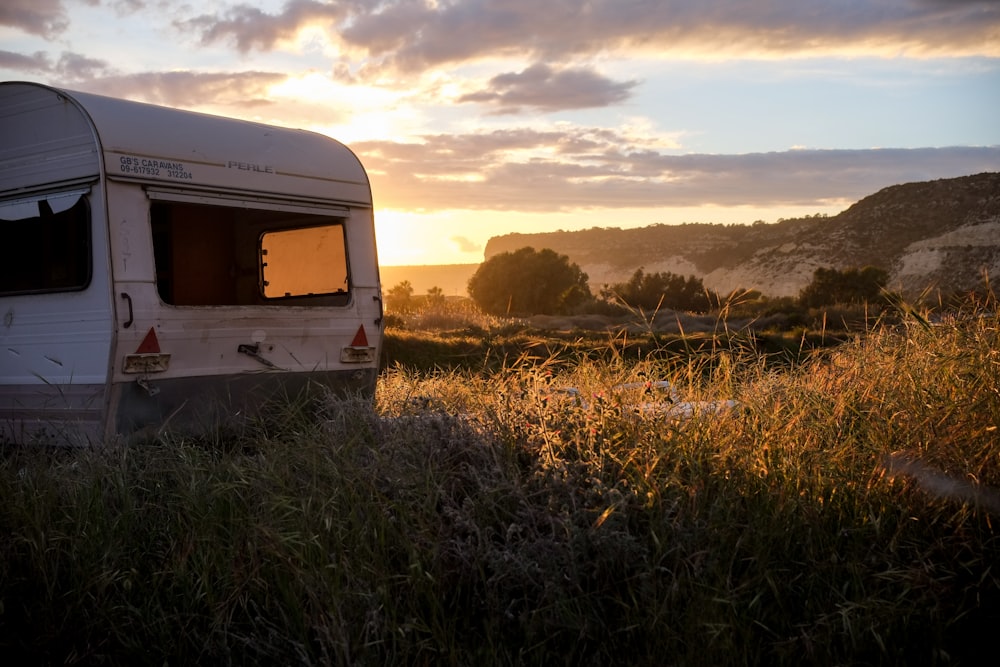 a camper parked in a field with the sun setting