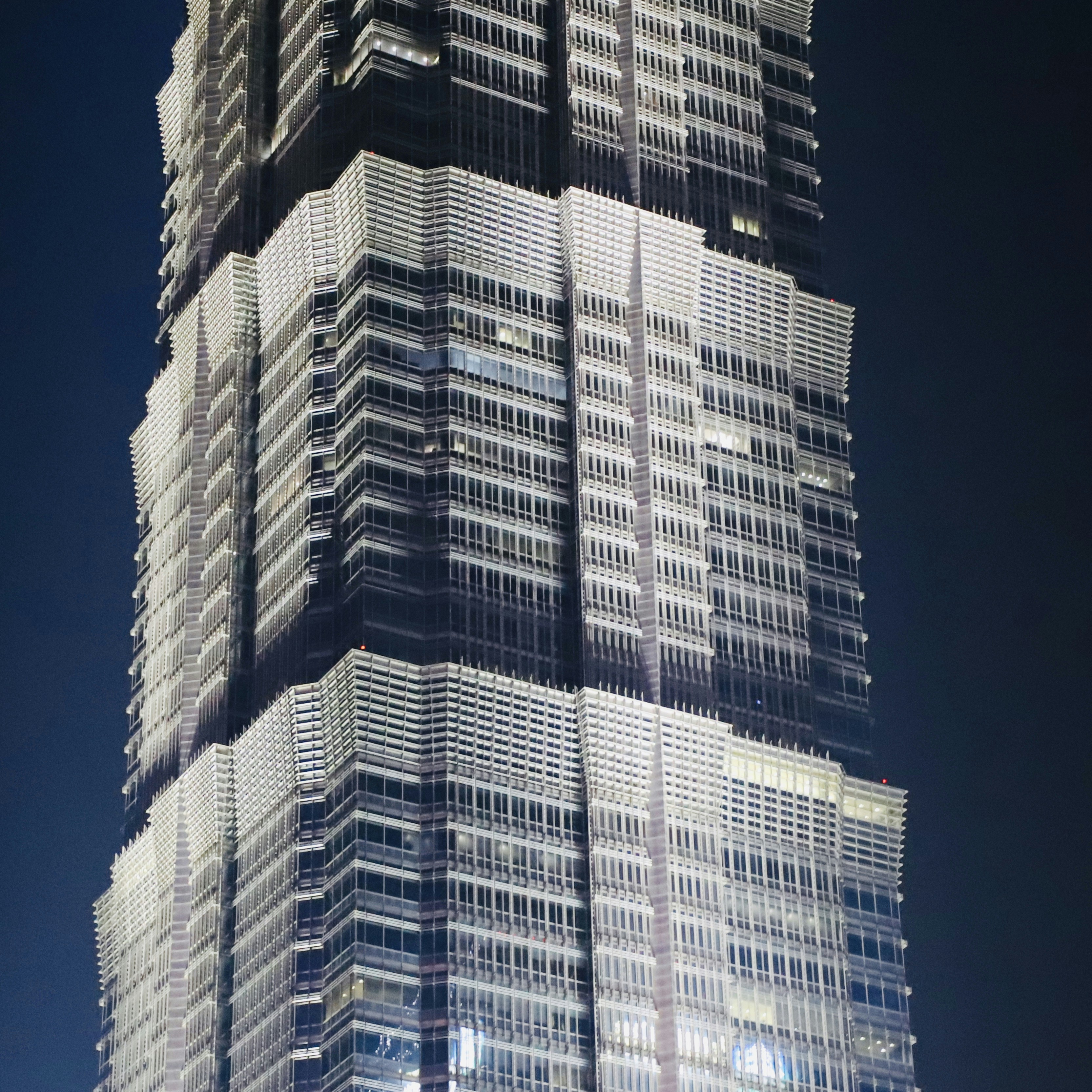 Corporate building facade at night with lit windows, dark sky, financial district atmosphere