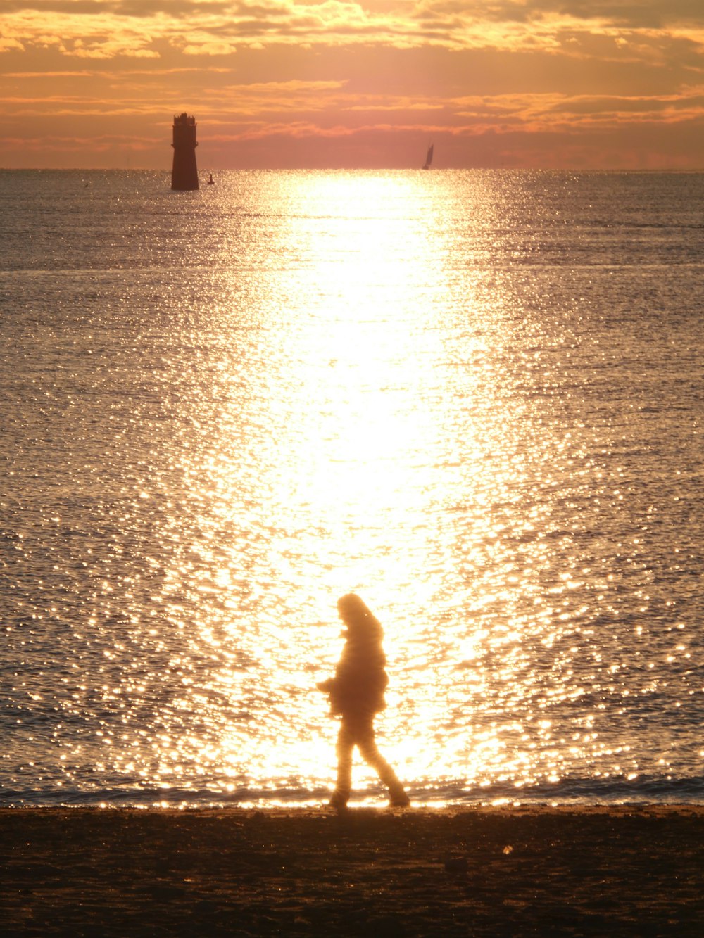 a person walking on the beach at sunset