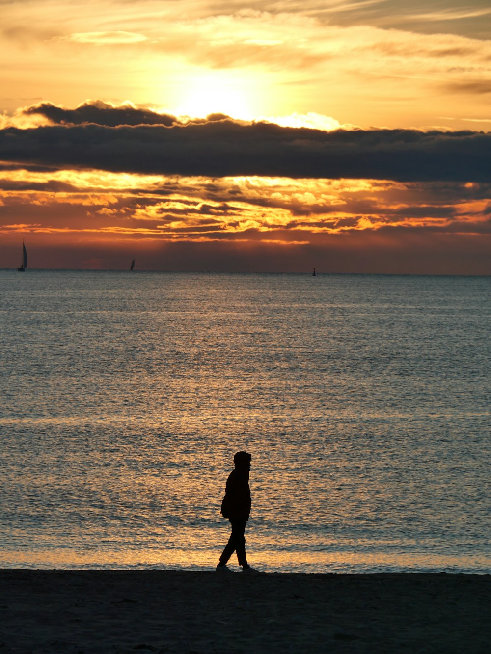 a person walking on the beach at sunset