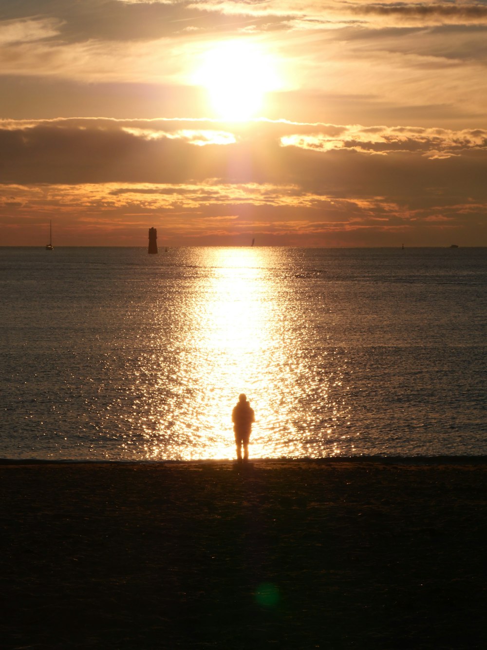 a person standing on a beach watching the sun set
