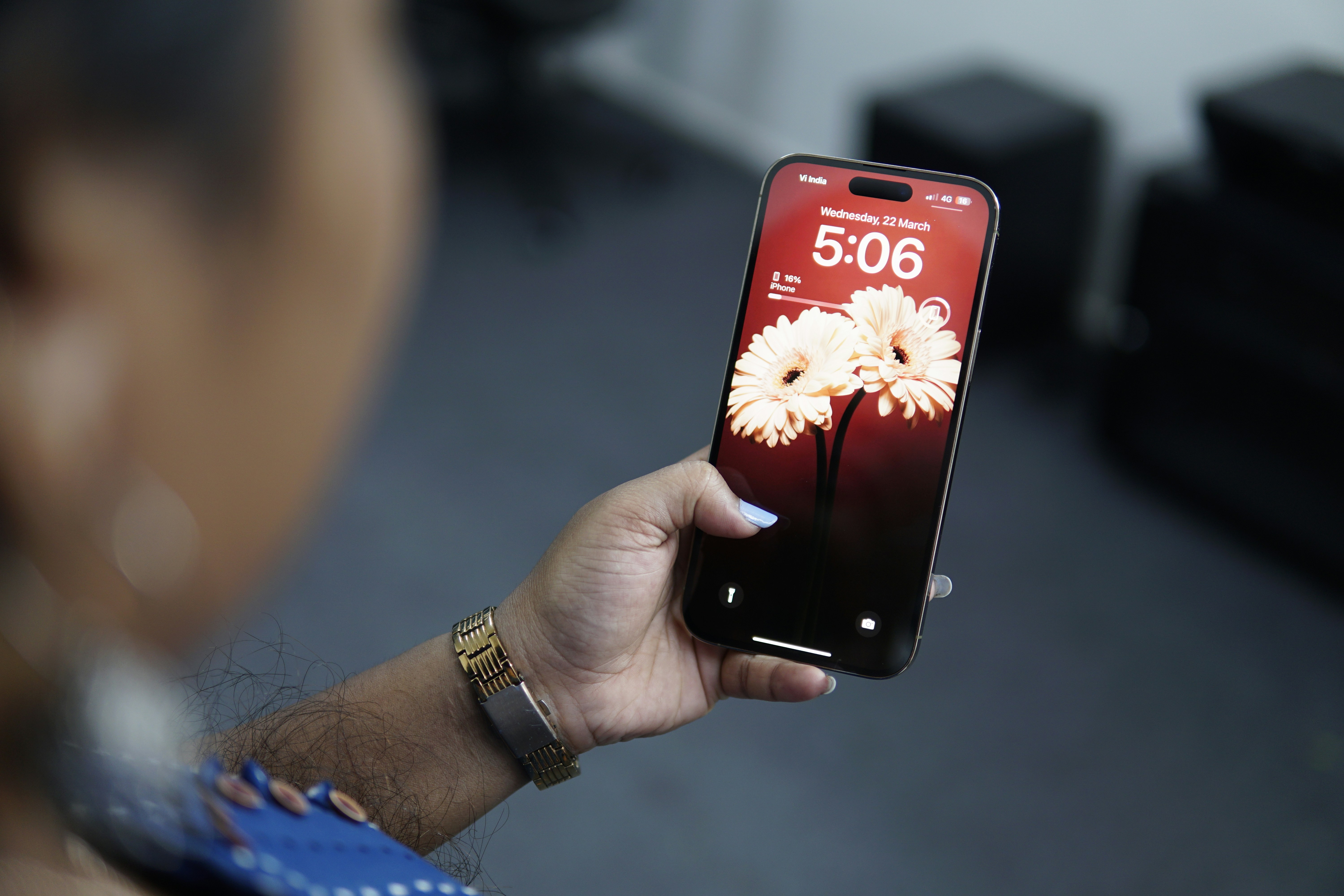 a woman holding a cell phone with a picture of flowers on it